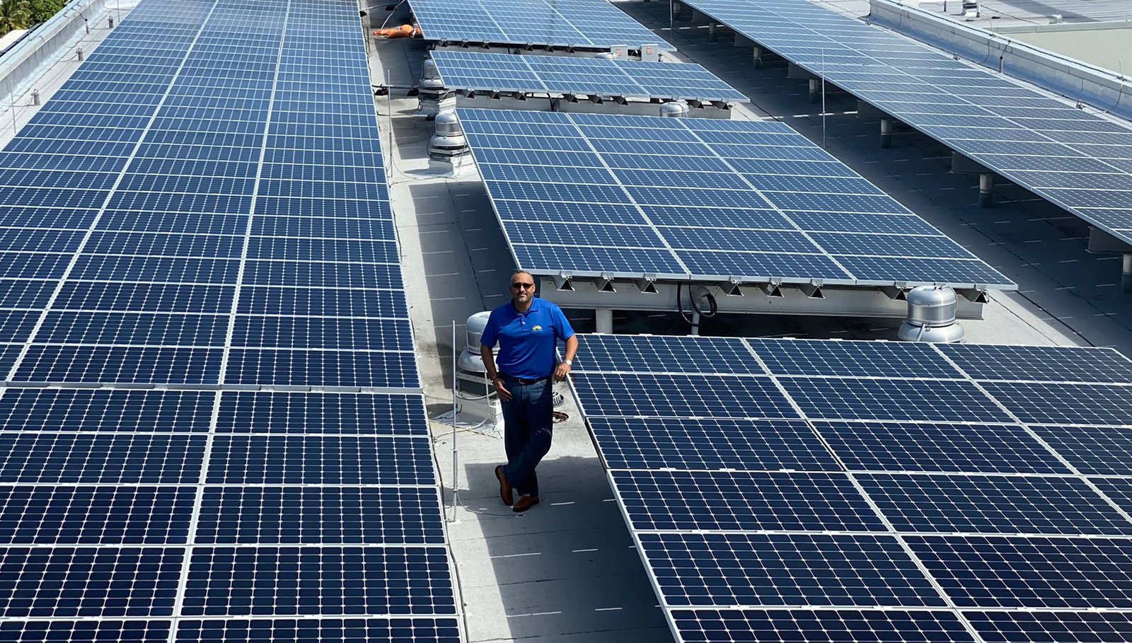 James Whittaker of GreenTech Energy walking between rows of rooftop solar panels